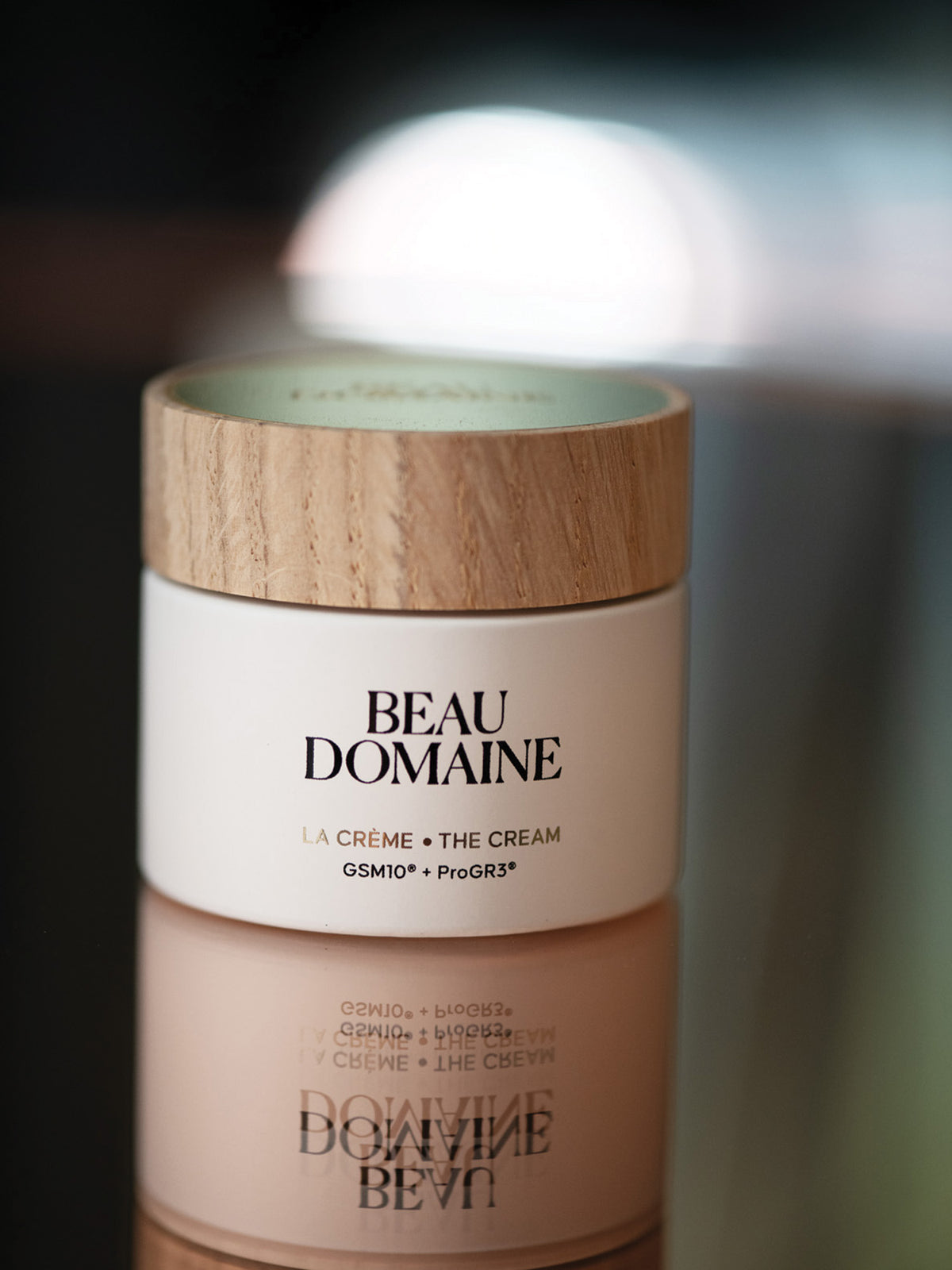Beau Domaine cream jar with wooden lid on a blurred background