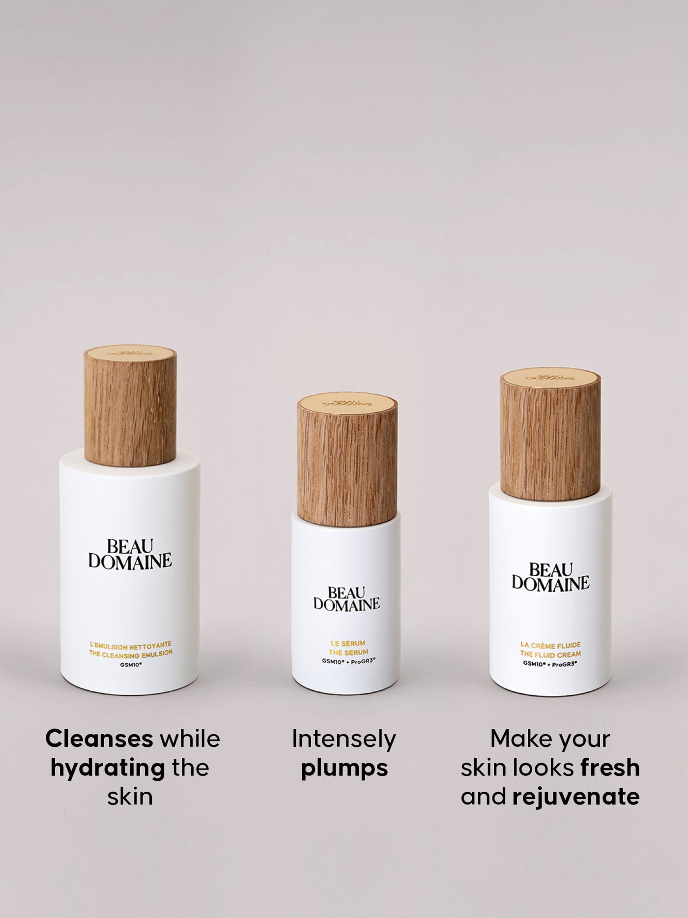 Three BEAU DOMAINE skincare bottles with wooden caps on a light gray background.
