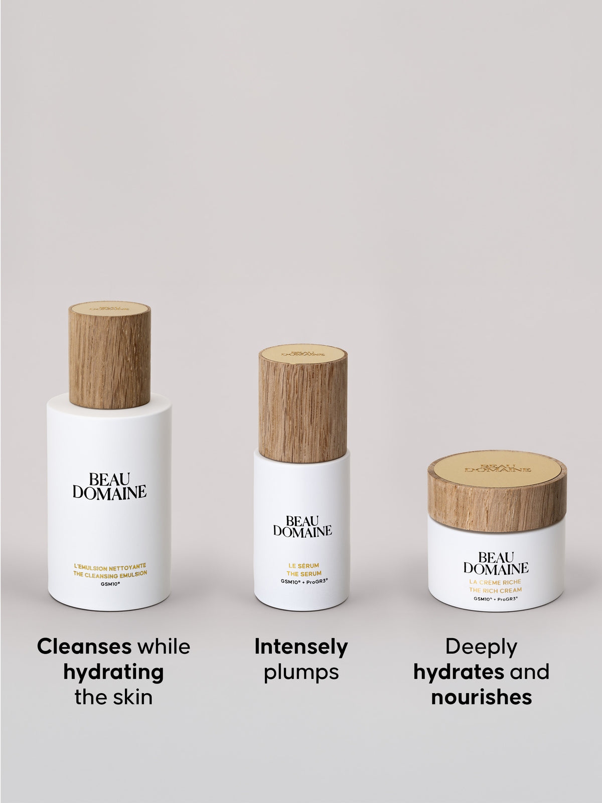 Three Beau Domaine products containing Cleansing Emulsion, Serum, and Rich Cream in its jar, all three arranged in a row, with a plain beige background and a caption presenting the products below each one. 