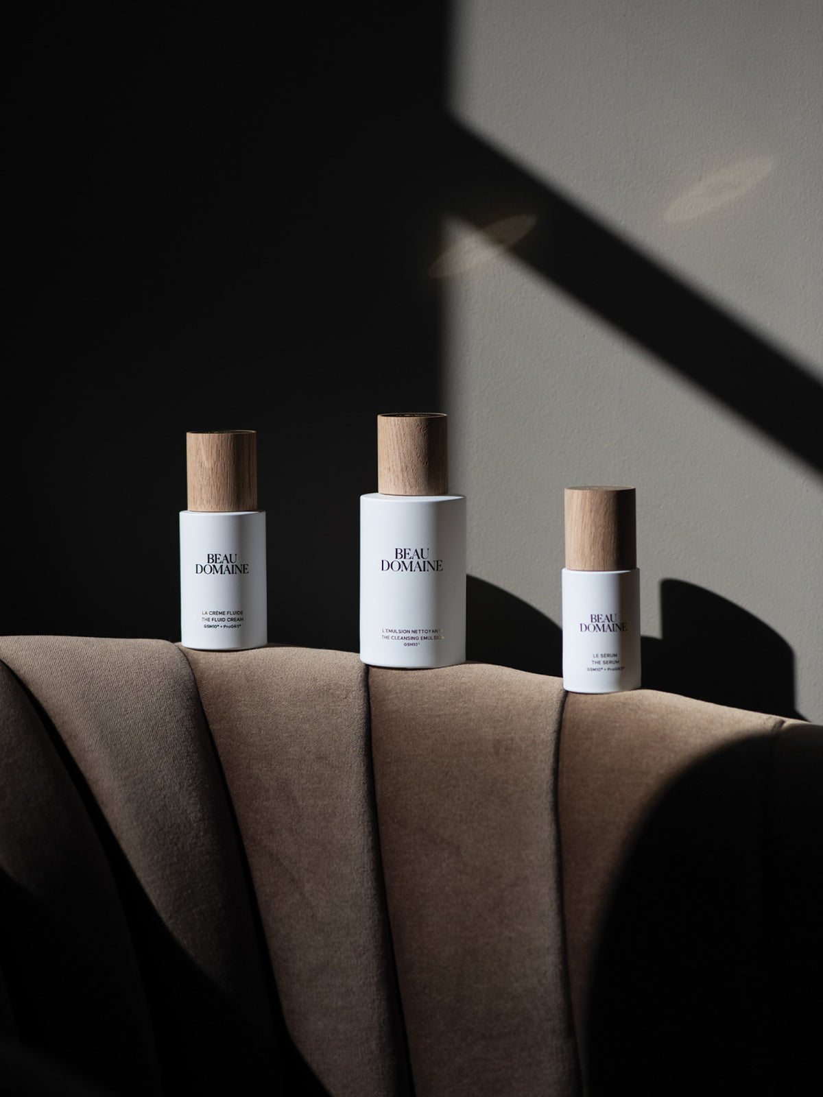 Three bottles of 'Beau Domaine' on a textured surface with a dark background