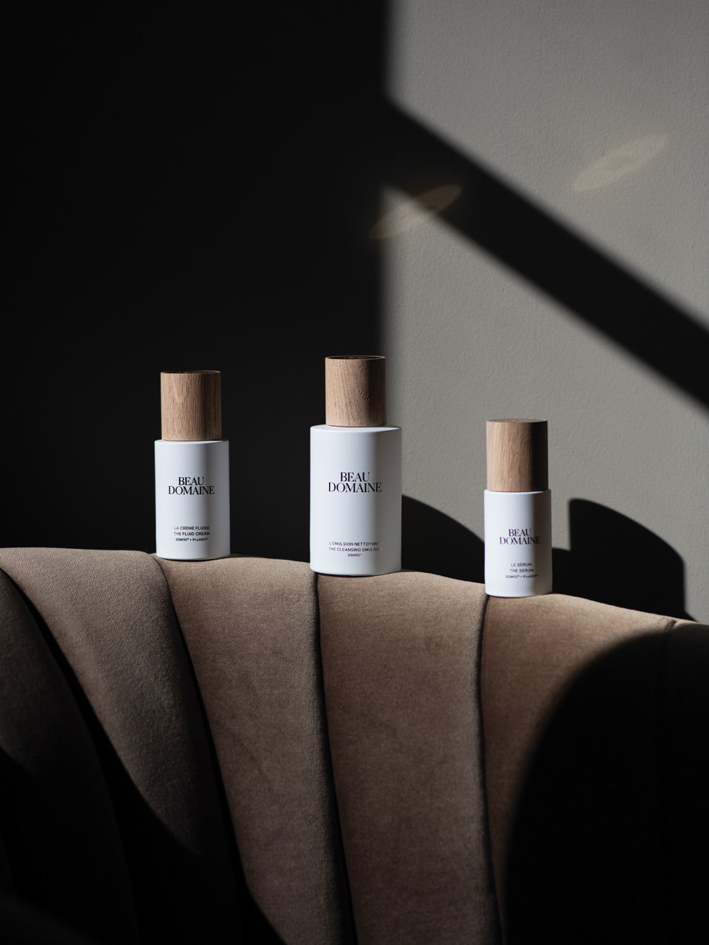 Three bottles of 'Beau Domaine' on a textured surface with a dark background