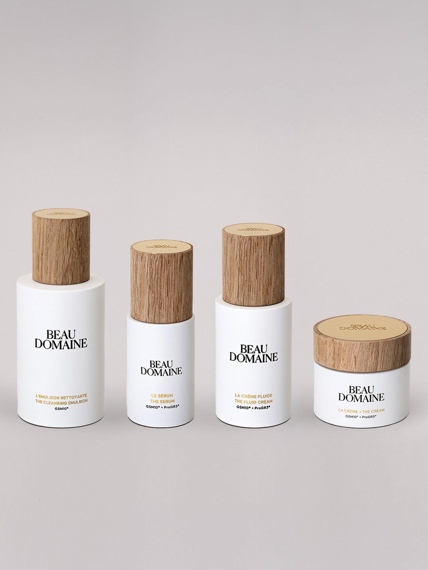 Four BEAU DOMAINE skincare products with wooden caps on a light gray background