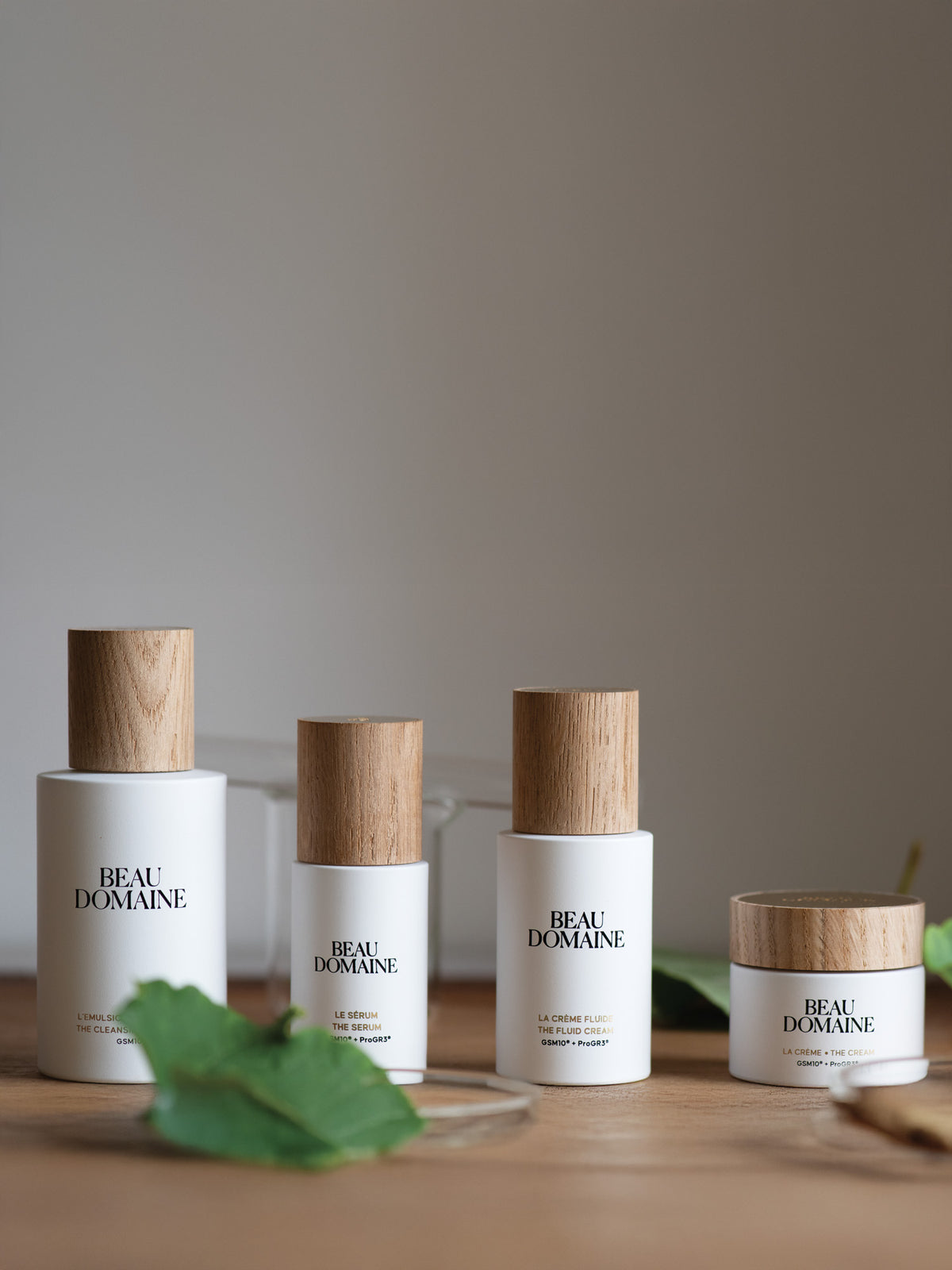 Four 'Beau Domaine' skincare products on a wooden surface with a neutral background